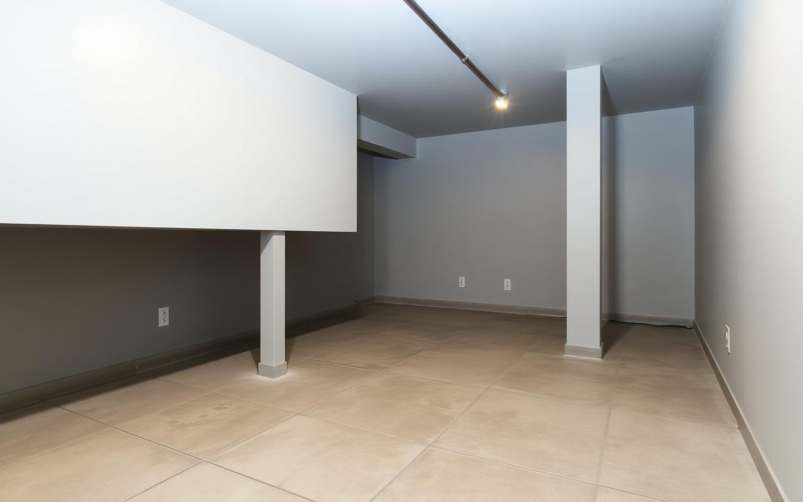 Clean, dry finished basement with sealed floor and light gray walls