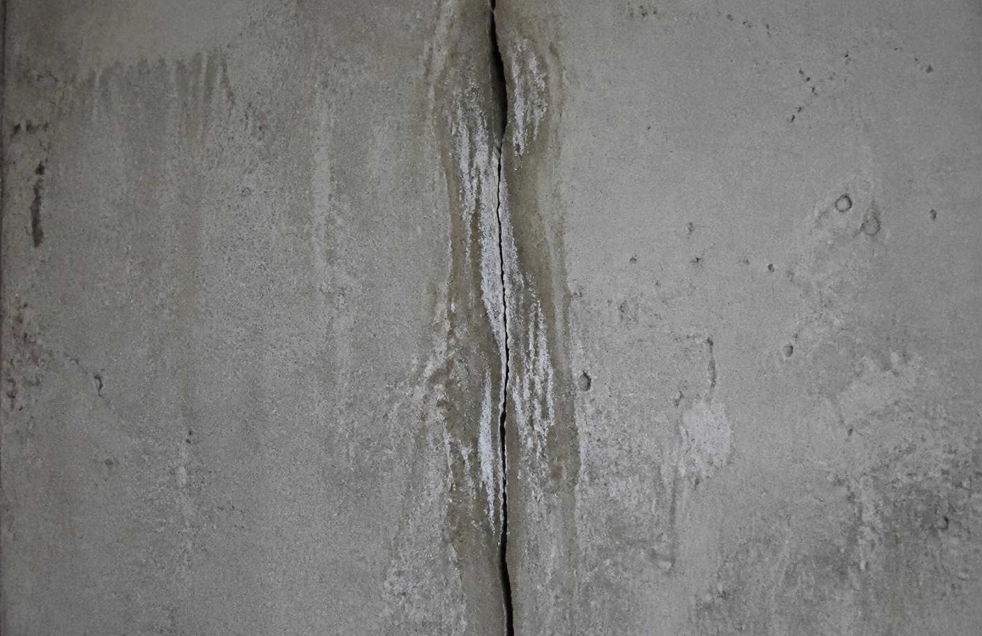 Vertical crack with mineral deposits in a poured concrete foundation wall